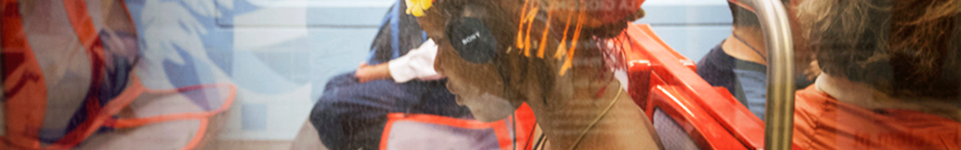 Close up image of a young girl with headphones seated inside a train