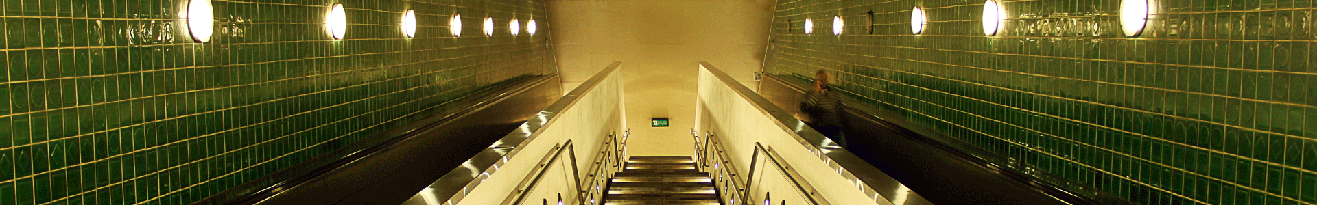  Image of escalators at a station with a passenger going down them