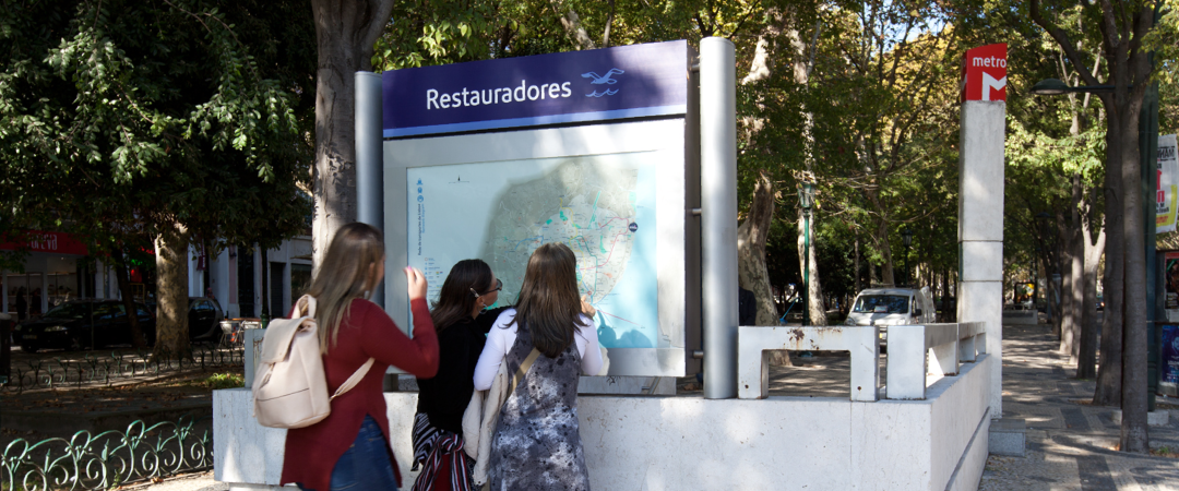 Diagramas e mapas Fotografia com três raparigas jovens junto a um acesso do Metro, olhando para um mapa da cidade e Metro.