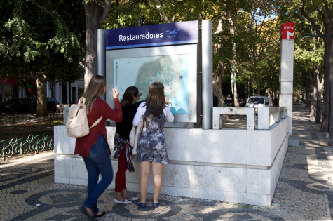 Mapas e diagramas Fotografia com três raparigas jovens junto a um acesso do Metro, olhando para um mapa da cidade e Metro.