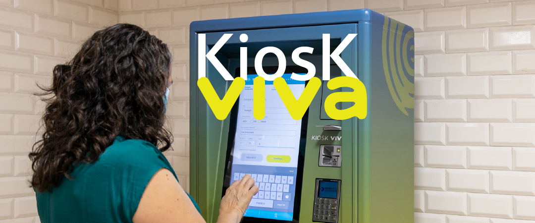 Senhora a utilizar um kiosk viva na estação Alameda. No topo e centro da imagem lemos "Kiosk viva"